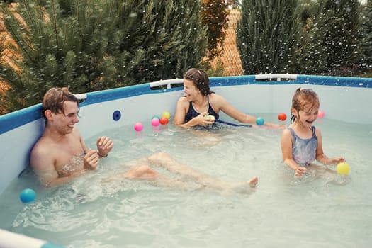 Children splashing, jumping, playing in a pool in backyard on summer vacation day. Real people, authentic situations