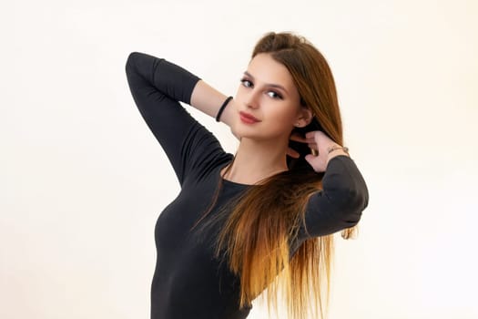 Side view of attractive brunette girl posing with hands in her hand on the light background.