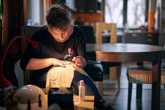 Woman doing manicure at home. Panting fingernails with hybrid nail polish. Woman using UV Led nail lamp to manicure