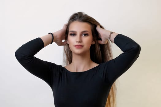 Front view of attractive brunette girl posing with hands in her hand on the light background. Horizontally.