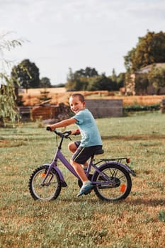 Happy smiling boy riding a bike, learning to ride a bike, in home garden. Real people, authentic situations