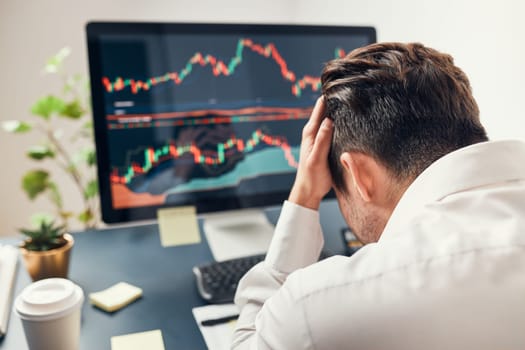 Worried businessman looking at charts stressed by news from stock market. Investor lost money online. Man analyses loss and profit. Businessman investing stocks online. Man working with stock chart data. Business investing trouble concept