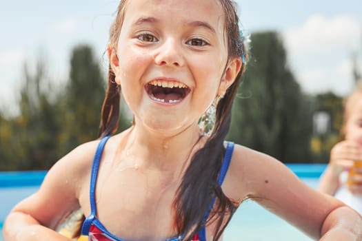 Portrait of happy smiling girl standing in a pool having fun on a summer sunny day. Close up of smiling kid looking at camera