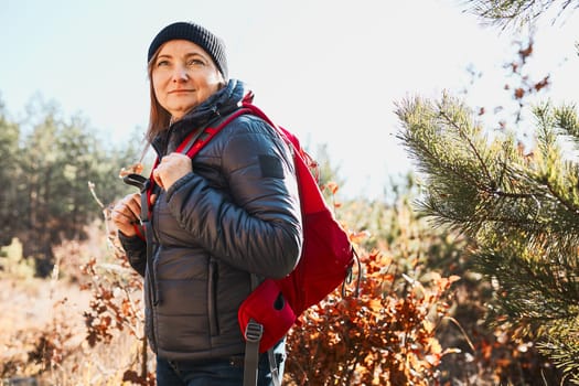 Happy woman enjoying hike on sunny vacation day. Female with backpack walking through forest. Spending summer vacation close to nature