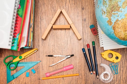School accessories, pencil, pen, scissors and wooden alphabet character on a wooden desk. View from above
