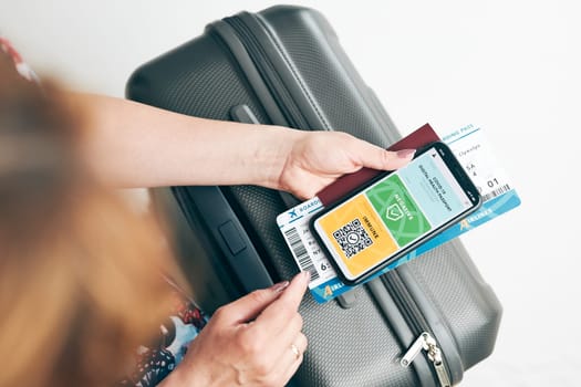 Digital covid certificate. Covid negative rapid digital test pass. Woman passenger holding digital medical pass on her mobile phone, passport and airplane ticket. Traveler showing digital covid test result as medical pass for travel during covid-19 pandemic