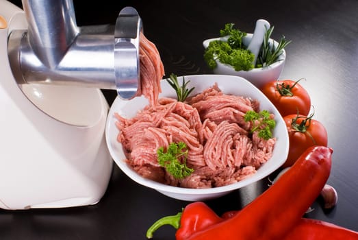 Bowl of mince with electric meat grinder and vegetables