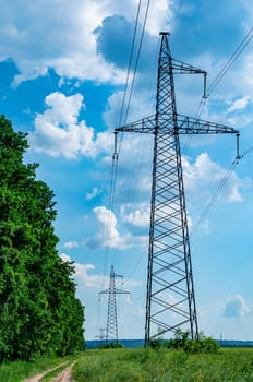 Tower with high-voltage energy transmission wires against the blue sky. High-voltage tower. Electrical wires and fuses. Energy business. Energy industry. Import and export of energy. Blue sky.