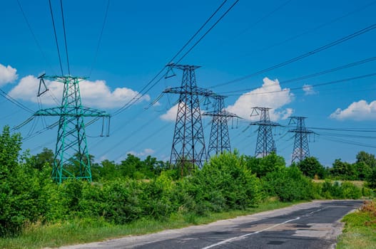 Tower with high-voltage energy transmission wires against the blue sky. High-voltage tower. Electrical wires and fuses. Energy business. Energy industry. Import and export of energy. Blue sky.