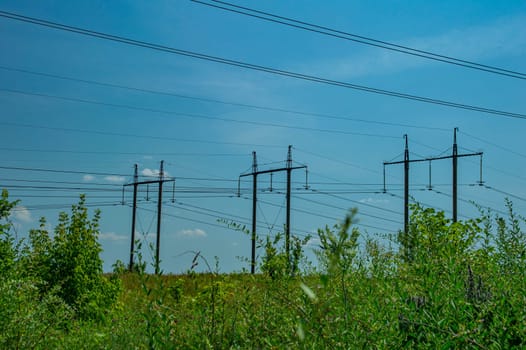 Tower with high-voltage energy transmission wires against the blue sky. High-voltage tower. Electrical wires and fuses. Energy business. Energy industry. Import and export of energy. Blue sky.