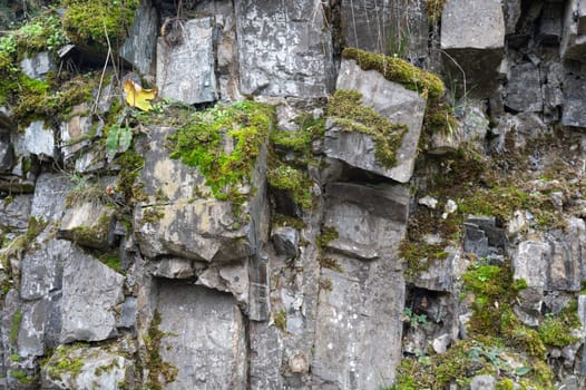 High rocky stone wall with green moss