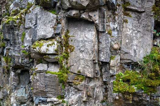 High rocky stone wall with green moss