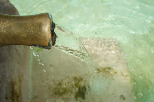 Water permanently flowing from a pipe of a public fountain. Concept of drinking water supply in ancient times