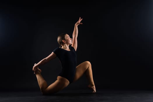 Flexible girl, rhythmic gymnastic artist jumping on white dark background. Grace in motion, action.