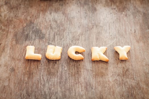 Lucky alphabet biscuit on wooden table, stock photo