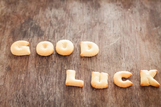 Good luck alphabet biscuit on wooden table, stock photo