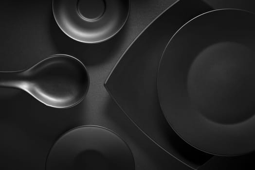 Top view of black empty plates on dark grey background.