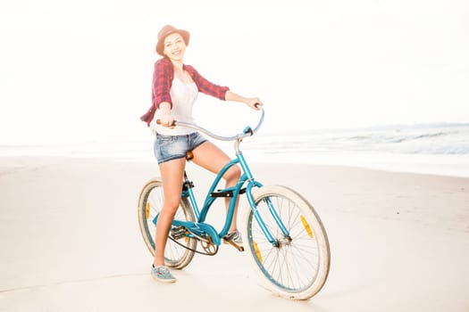 An attractive young woman riding her bicycle on the beach