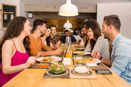 Multi-Ethnic Group of happy friends lunching and having fun at the restaurant