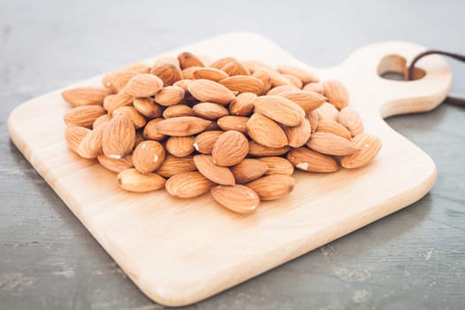 Almond nuts on wooden plate, stock photo