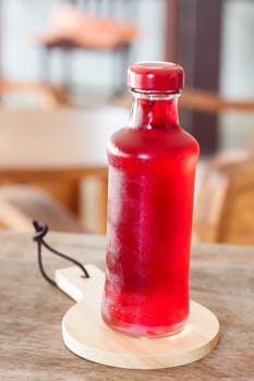 Red syrup in the bottle on wooden plate, stock photo
