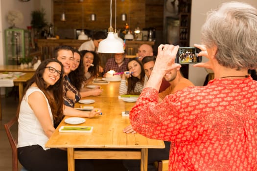 Granny taking a picture of all family celebrating the birthday grandfather