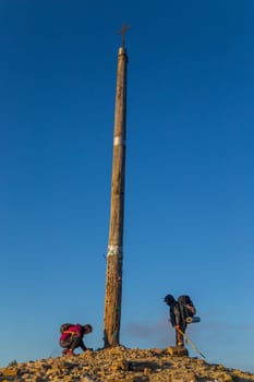 Foncebadon, Spain - 20 August 2022: Pilgrims next to the iron cross called cruz de Hierro along the way of St. James