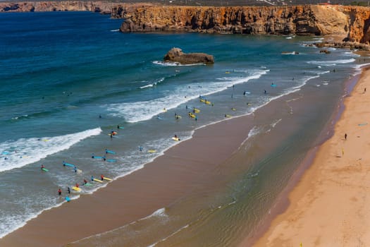 Sagres, Portugal - August 25, 2022: View of surfers on sandy beach near Sagres village in Algarve, Portugal