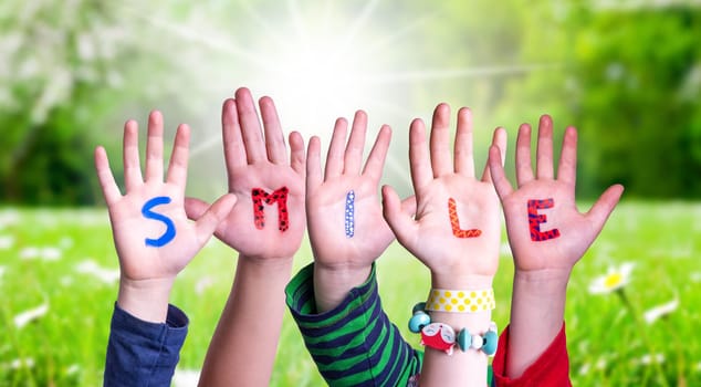 Children Hands Building Colorful English Word Smile. Sunny Green Grass Meadow As Background.