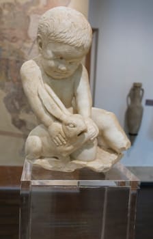 Cabra, Spain - May 19th, 2019: Child boy with hare. Archaeological Museum of Cabra Main Hall, Cordoba, Spain
