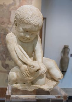 Cabra, Spain - May 19th, 2019: Child boy with hare. Archaeological Museum of Cabra Main Hall, Cordoba, Spain
