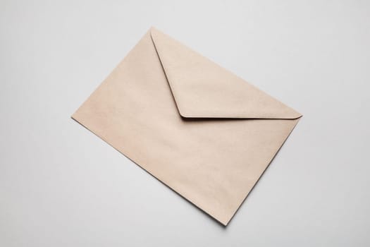 Photo of blank kraft paper envelope on gray paper background.