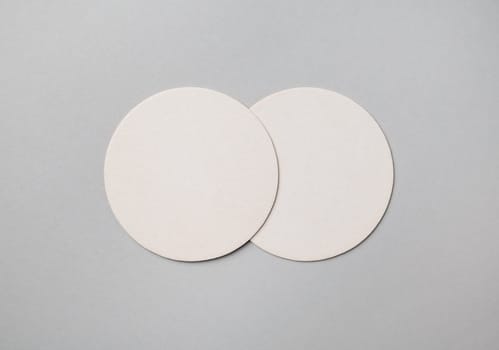 Two blank beer coasters on gray paper background. Responsive design mockup. Flat lay.