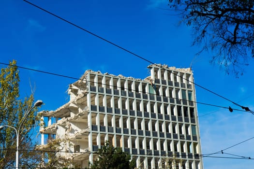 Demolition of a old building with sloopkraan against blue clouds sky.