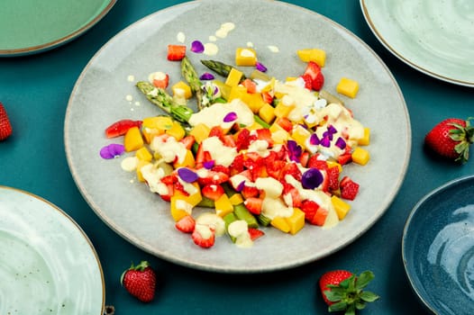 Light spring salad of berries, green asparagus, mango and yogurt. Copy space. Banner.