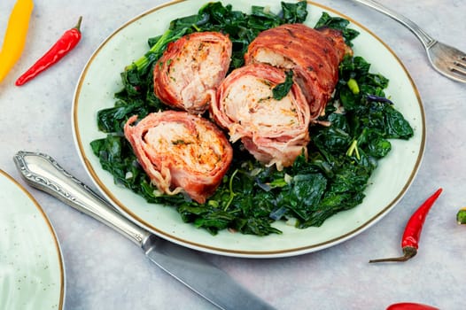 Sliced Baked chicken meat breast roll with fried spinach garnish.