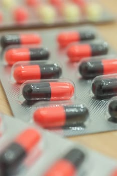 Medicine red and black in capsule on wood table, Selective focus