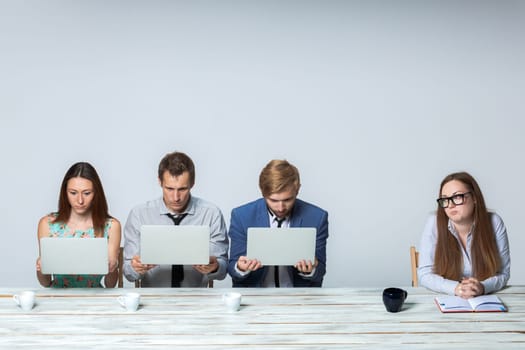 Business team working together at office on light gray background. all working on laptops. boss watching  the process. copyspace image