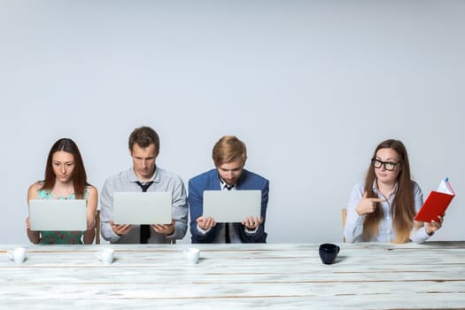 Business team working together at office on light gray background. all working on laptops. boss giving a task, all thinking. copyspace image