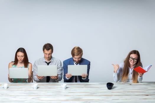 Business team working on their business project together at office on light gray background. all keeping computers. boss laughing. copyspace image.