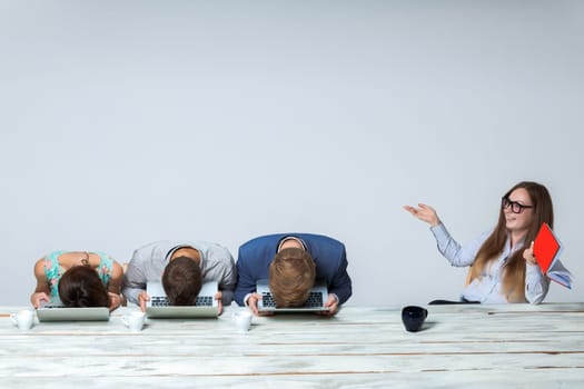 Business team working on their business project together at office on light gray background. all buried his head in the computer screen. boss laughing. copyspace image.