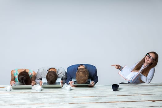 Business team working on their business project together at office on light gray background. all buried his head in the computer screen. boss laughing. copyspace image.
