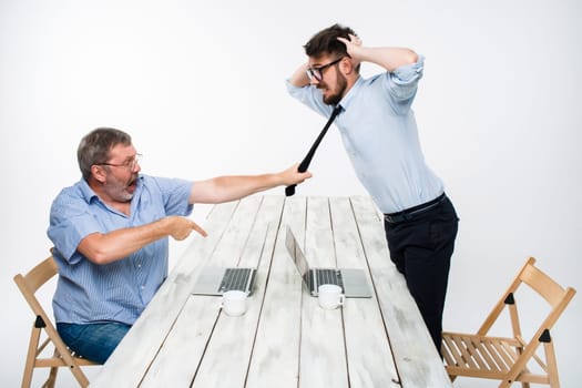 Business conflict. The two men expressing negativity while one man grabbing the necktie of her opponent on white background