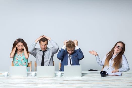 Business team working on their business project together at office on light gray background. all all grabbed his head. boss laughing. copyspace image.