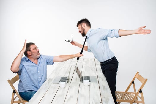 Business conflict. The two men expressing negativity while one man grabbing the necktie of her opponent on white background