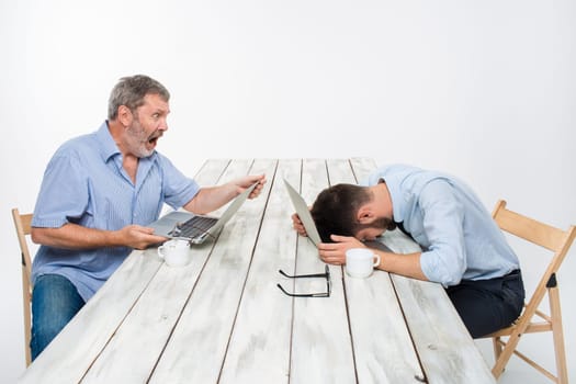 The two colleagues working together at office on white  background. man are looking at the computer screens. both very upset. another man putting his head on the computer. concept of negative emotions and bad news