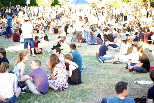 Mainz,Germany – July 09,2015: Young spectators and listeners sit on a meadow during a concert at the Asta Summer Festival on July 9,2015 in Mainz.