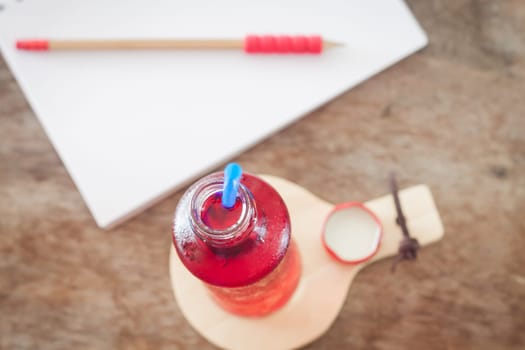 Red syrup in the bottle on wooden plate, stock photo