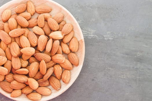 Almond nuts on wooden plate, stock photo