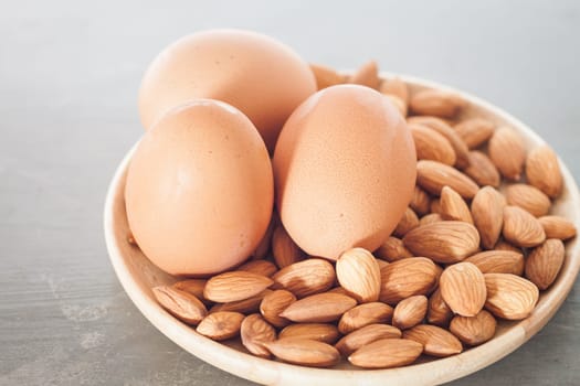 Almond nuts and eggs on wooden plate, stock photo